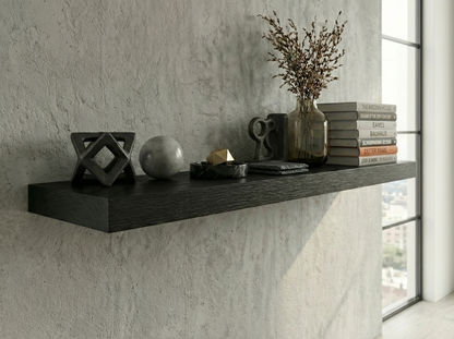 Decorative shelf with books, vase, and sculptures against a textured wall.