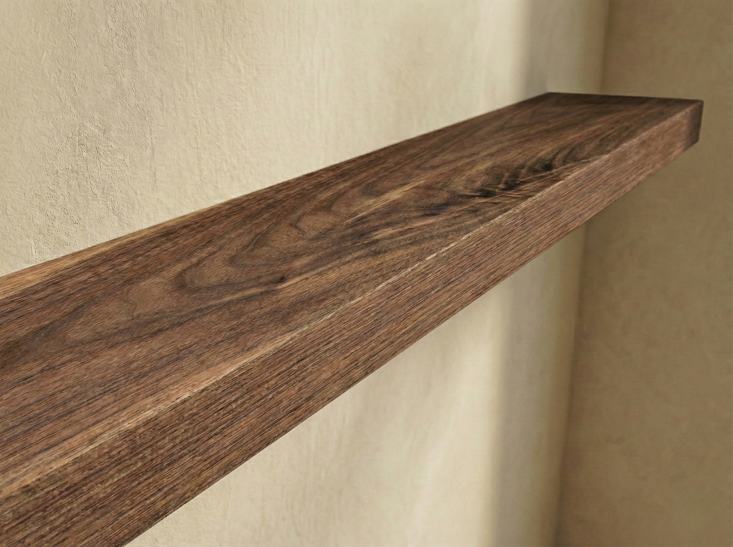 Close-up of a walnut hardwood floating shelf showcasing its rich grain and smooth finish by The Mortise & The Hare.